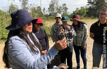mujer joven mostrando un hongo a un grupo de estudiantes